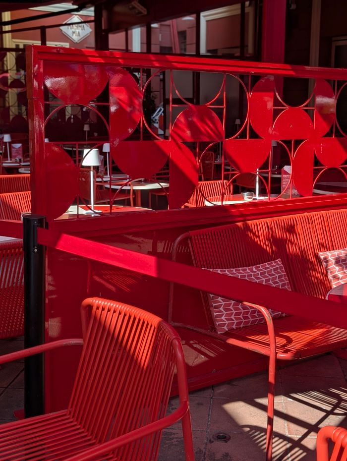 Bright red chairs and decor in an outdoor cafe in Nizza, France, exuding a modern summer vibe.