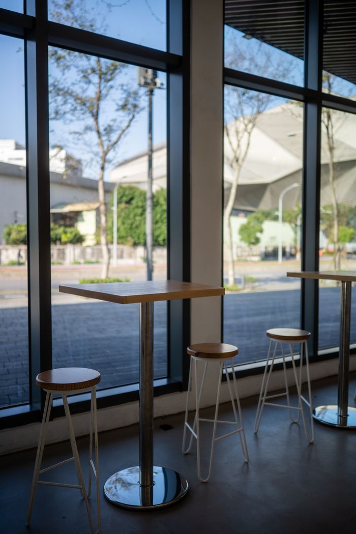 Bright modern cafe with high tables and stools by large windows overlooking the street.